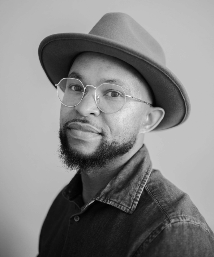 A professional headshot of illustrator AG Ford, looking toward the camera from his left with a warm expression.