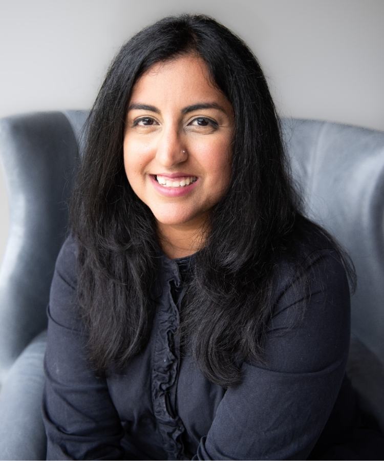 A professional headshot of NYT-bestselling author Aisha Saeed, smiling warmly in a bright and sophisticated portrait.