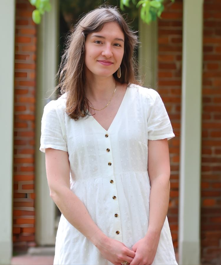 A professional headshot of graphic novel creator Brenna Thummler, smiling warmly in a stylish and creative portrait.