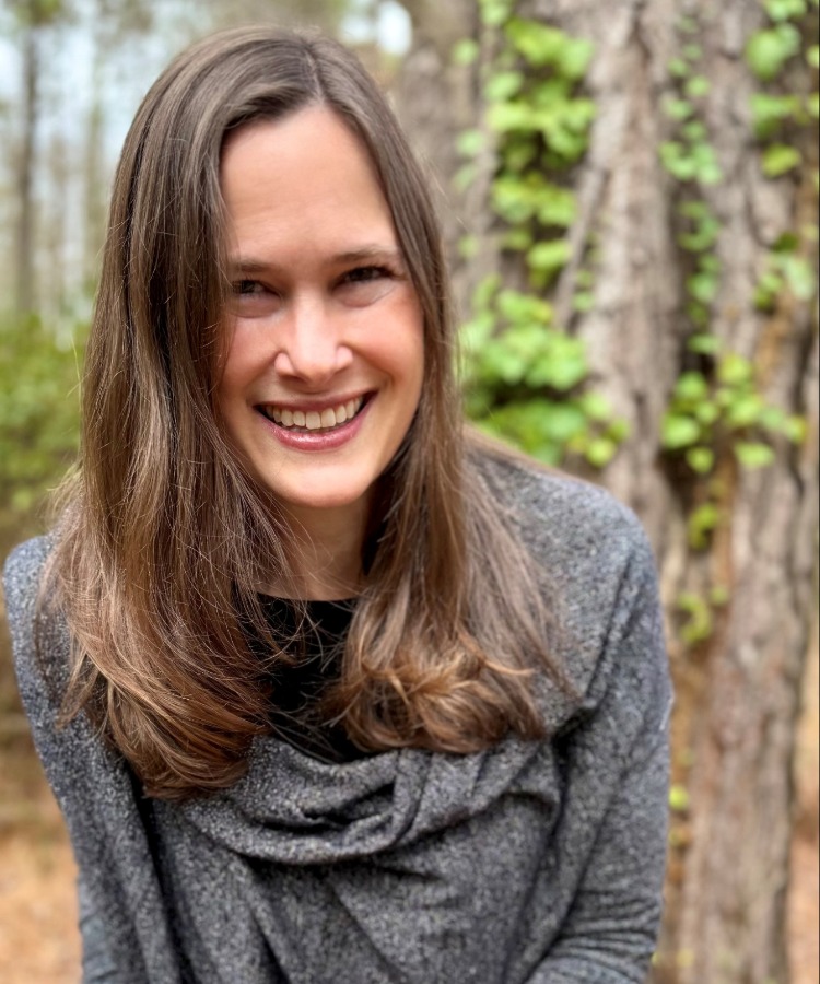 Author Melanie Dale smiling in a professional portrait with a scenic woods background.